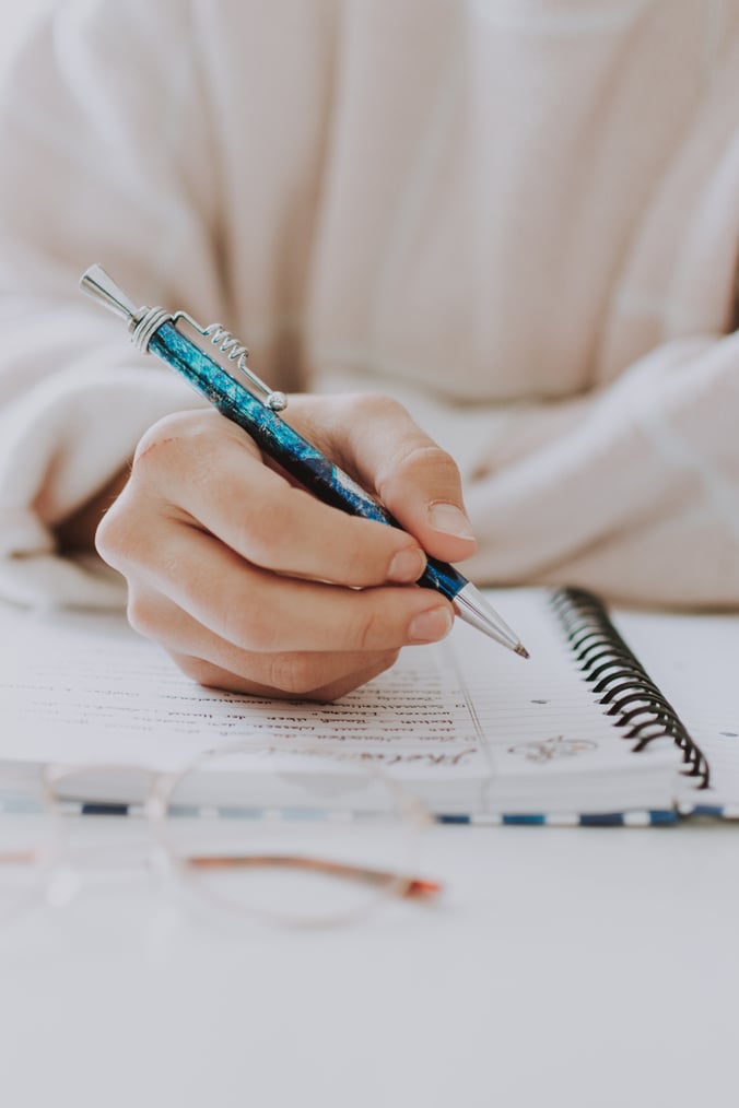 Woman with pen writing notes in notepad